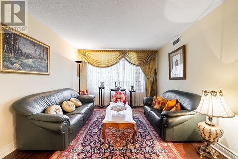 A living room with a black leather couch, a coffee table, and a painting on the wall.