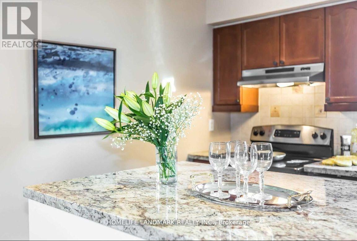 A kitchen counter with a vase of flowers, a plate with glasses, and a painting on the wall.