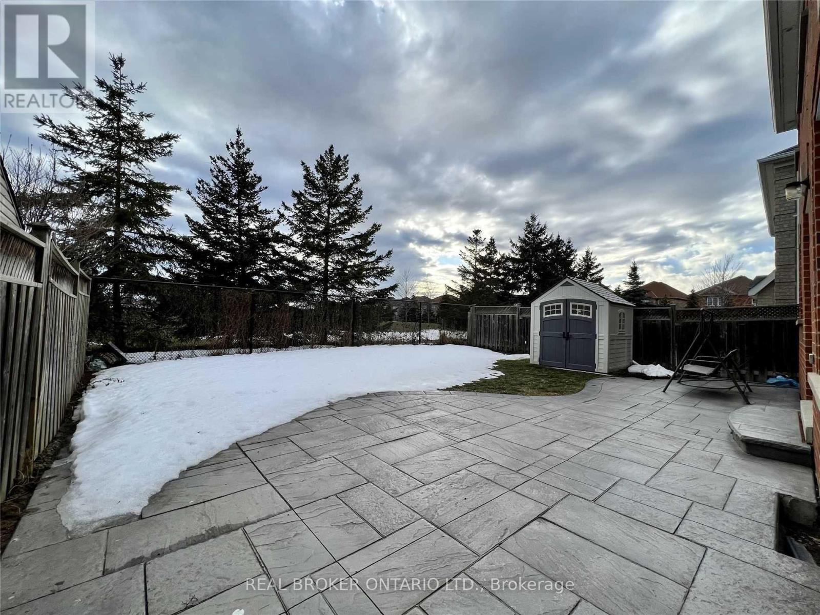 A backyard with a stone patio and a small building.