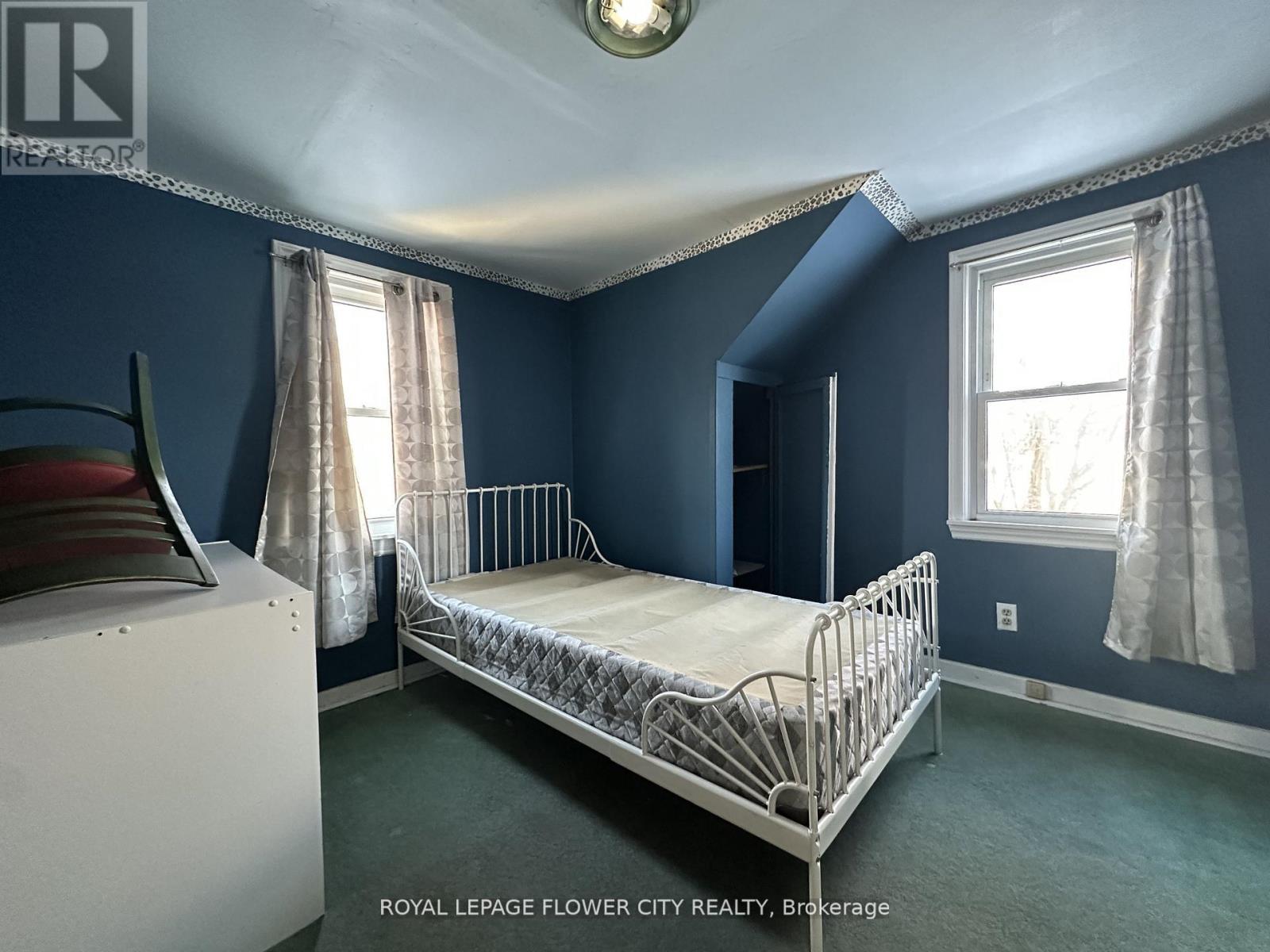 A bedroom with a white bed and a window with curtains.