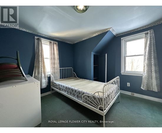 A bedroom with a white bed and a window with curtains.