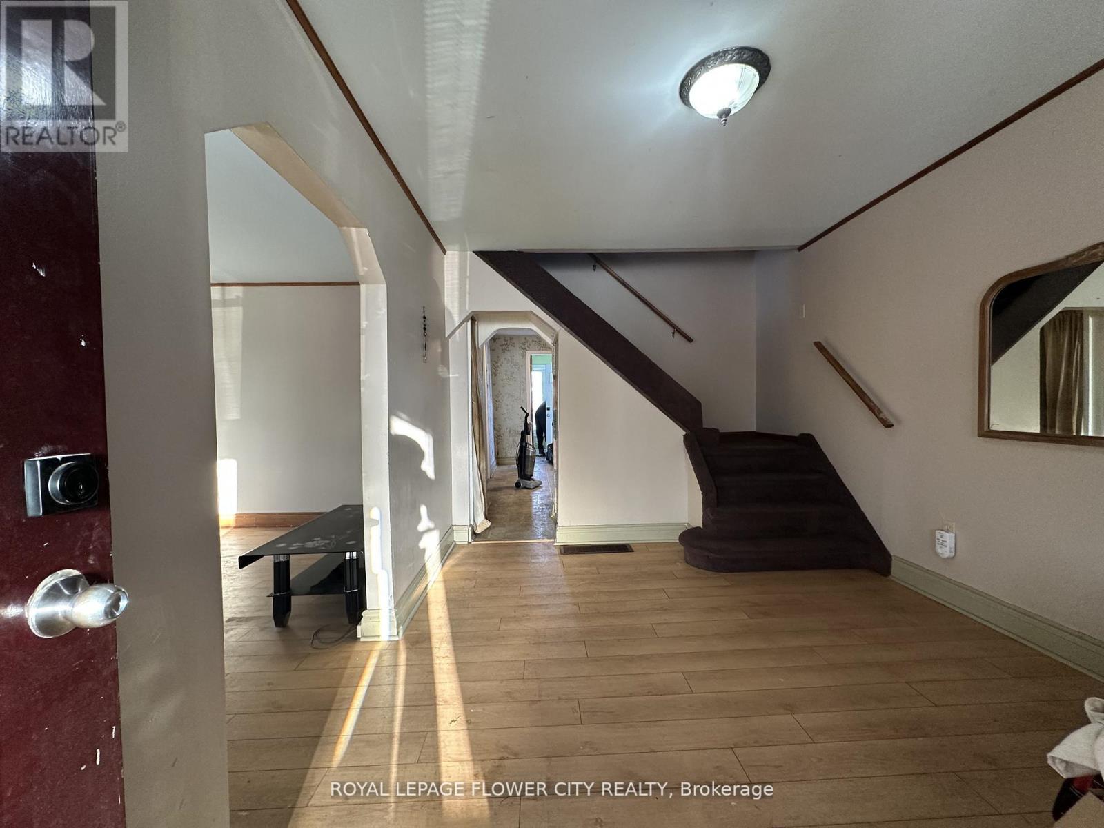 A hallway with a staircase and a person walking in the distance.