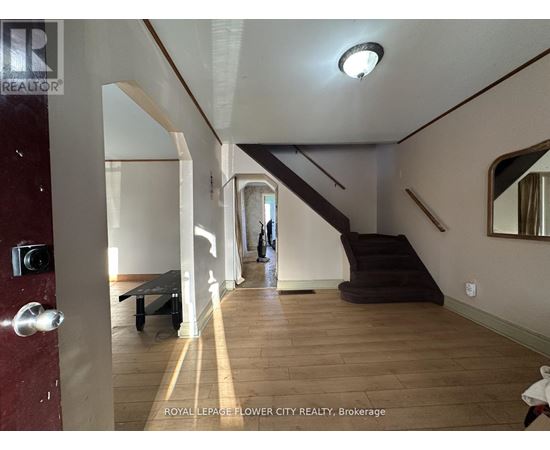 A hallway with a staircase and a person walking in the distance.