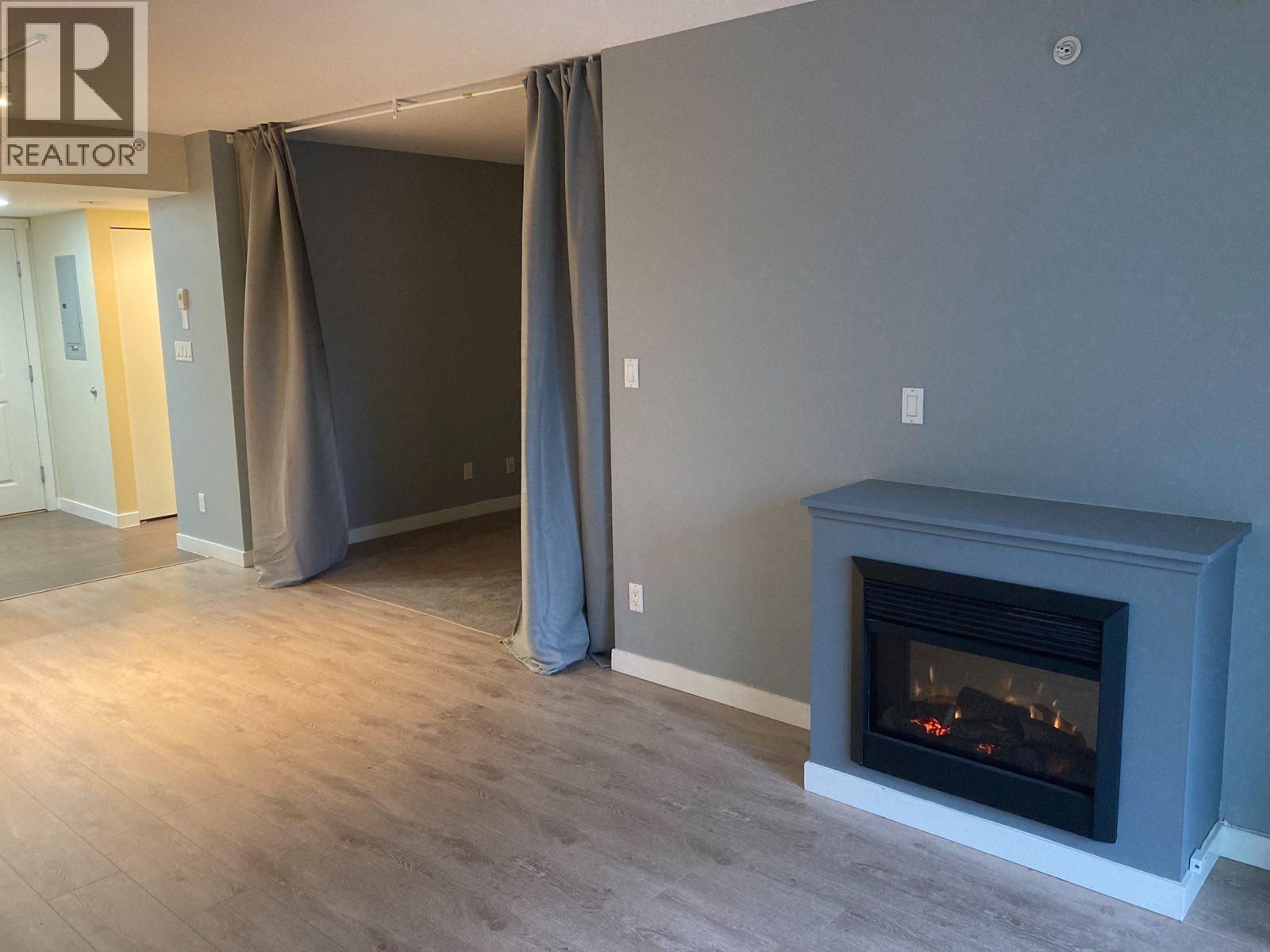 A living room with a fireplace and a realtor sign.