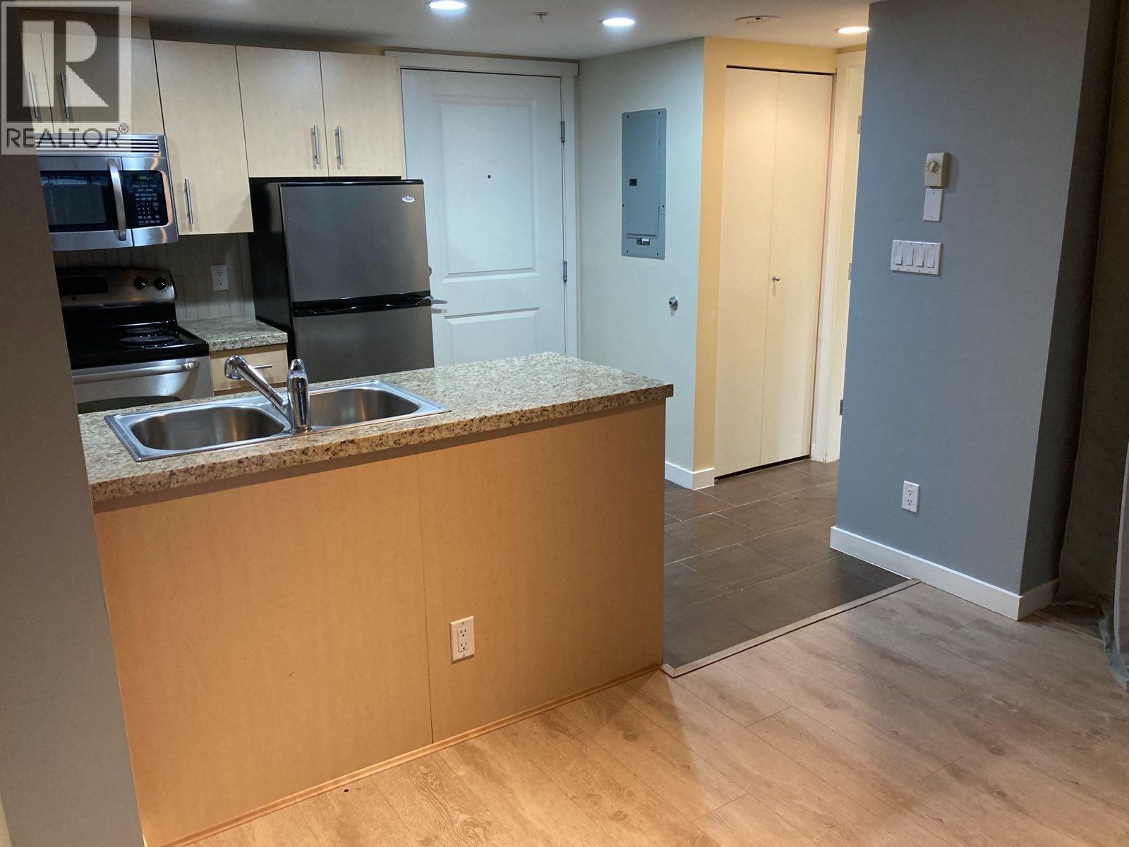 A kitchen with a sink, stove, and refrigerator.