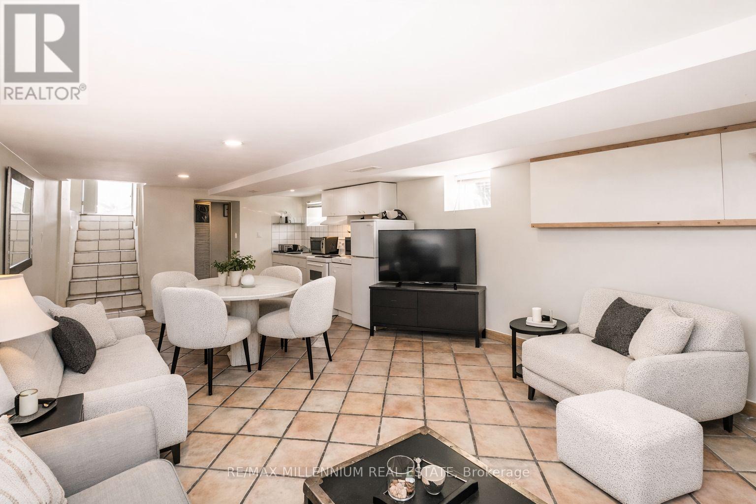 A living room with a white sofa set and a black television.