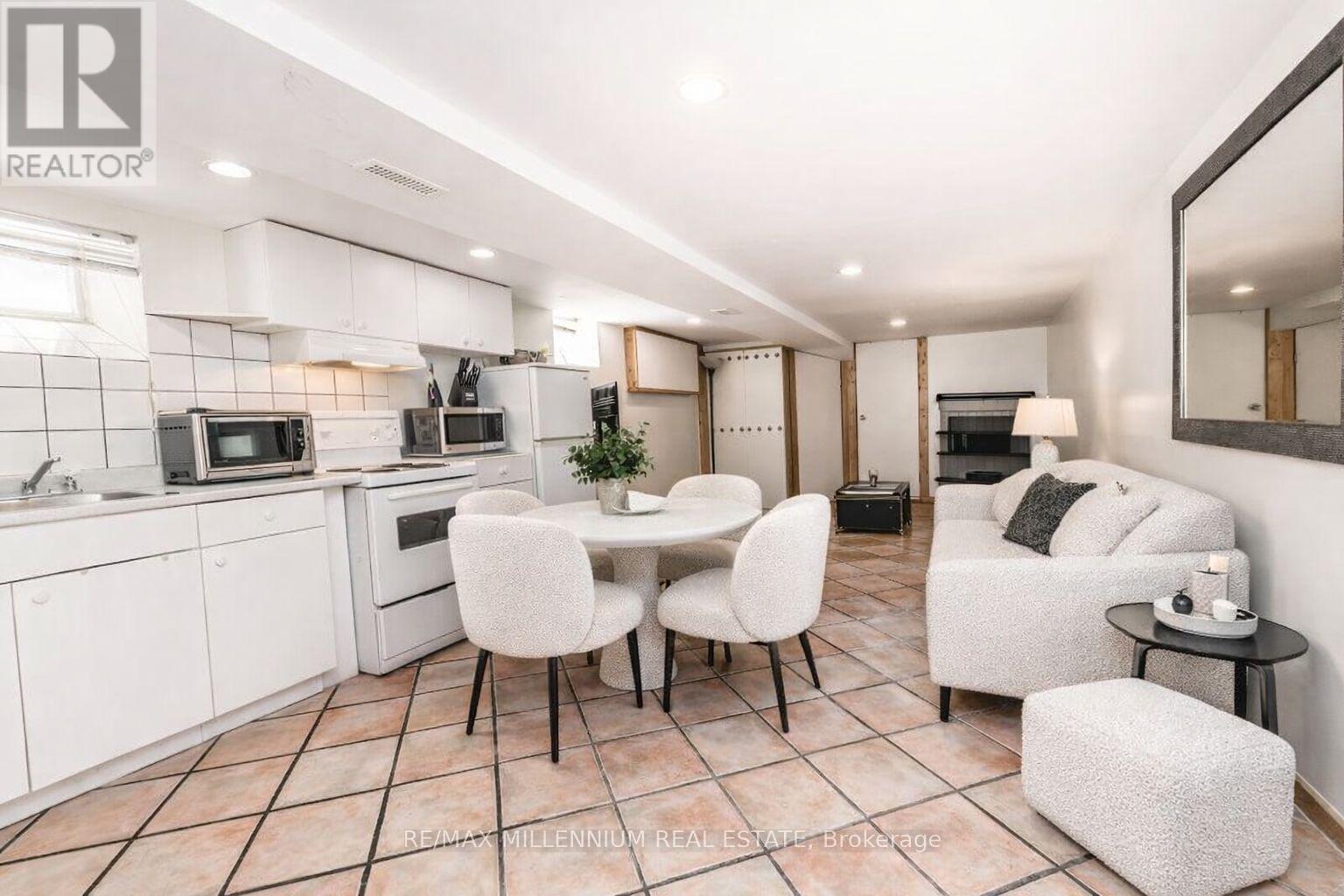 A modern kitchen with white cabinets and a dining area with white chairs.