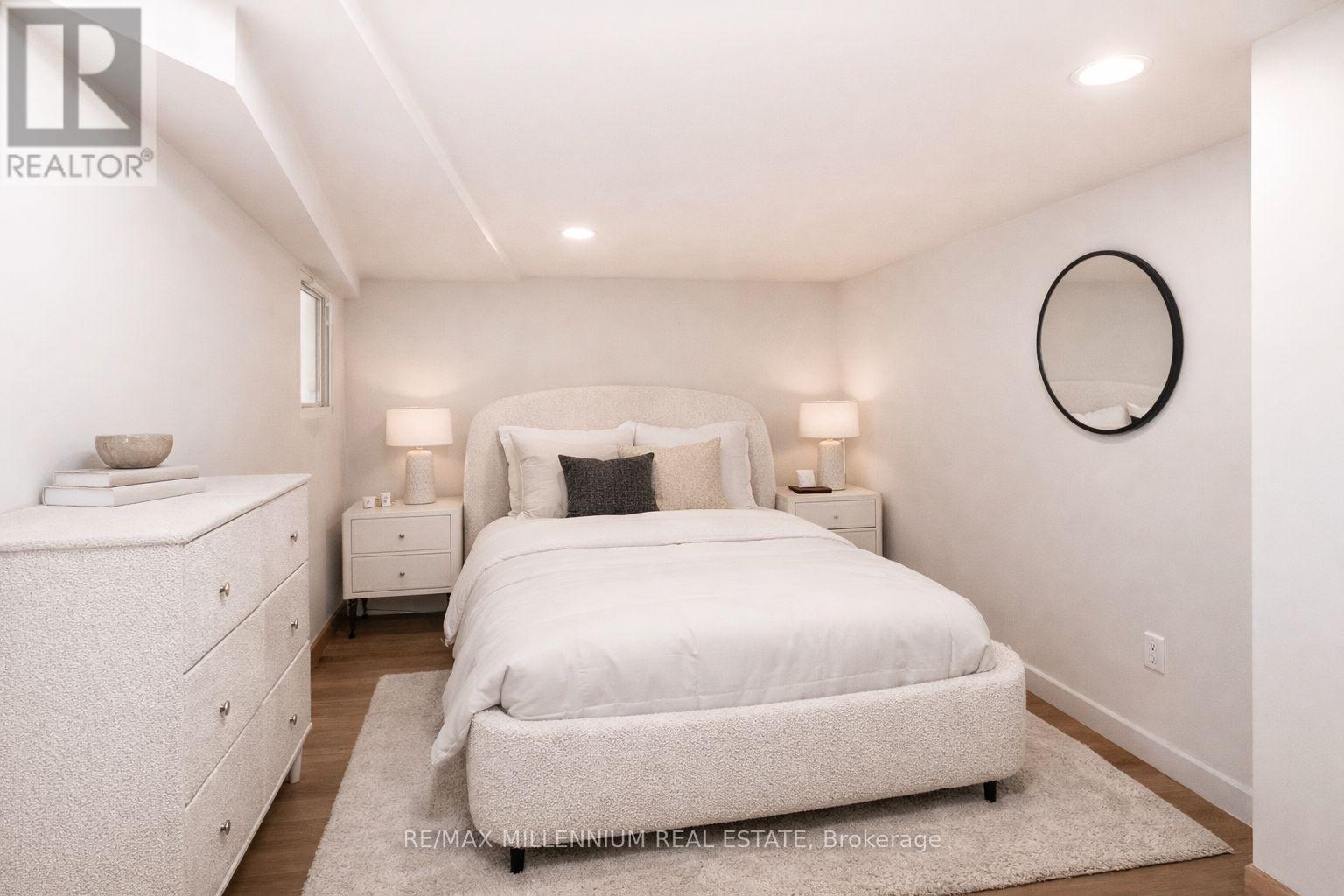 A white bedroom with a bed, nightstands, and a dresser.