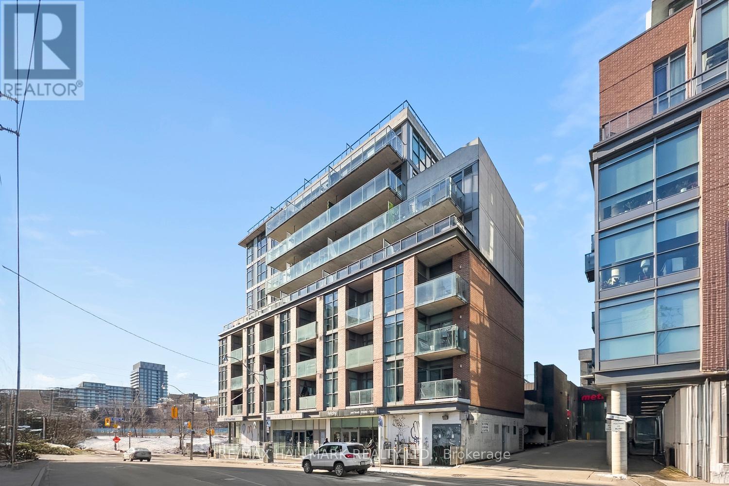 A modern multi-story building with a parking lot in front.