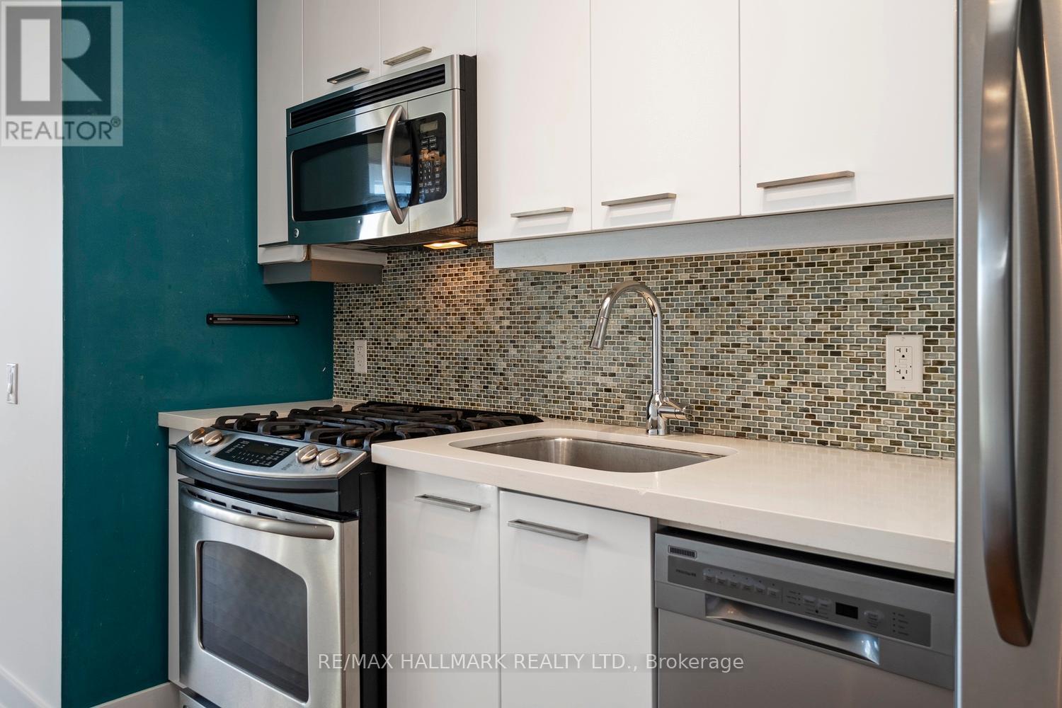 A kitchen with a stove, sink, and refrigerator.