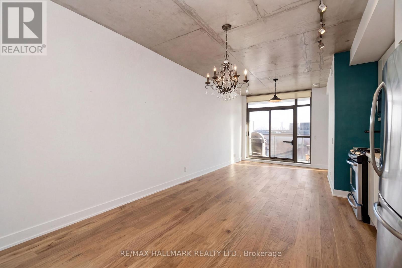 A spacious room with wooden flooring and a chandelier hanging from the ceiling.