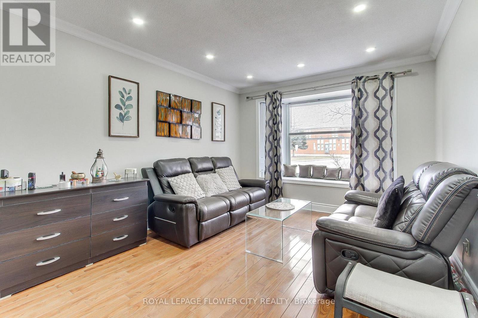 A living room with a black leather couch and a wooden floor.