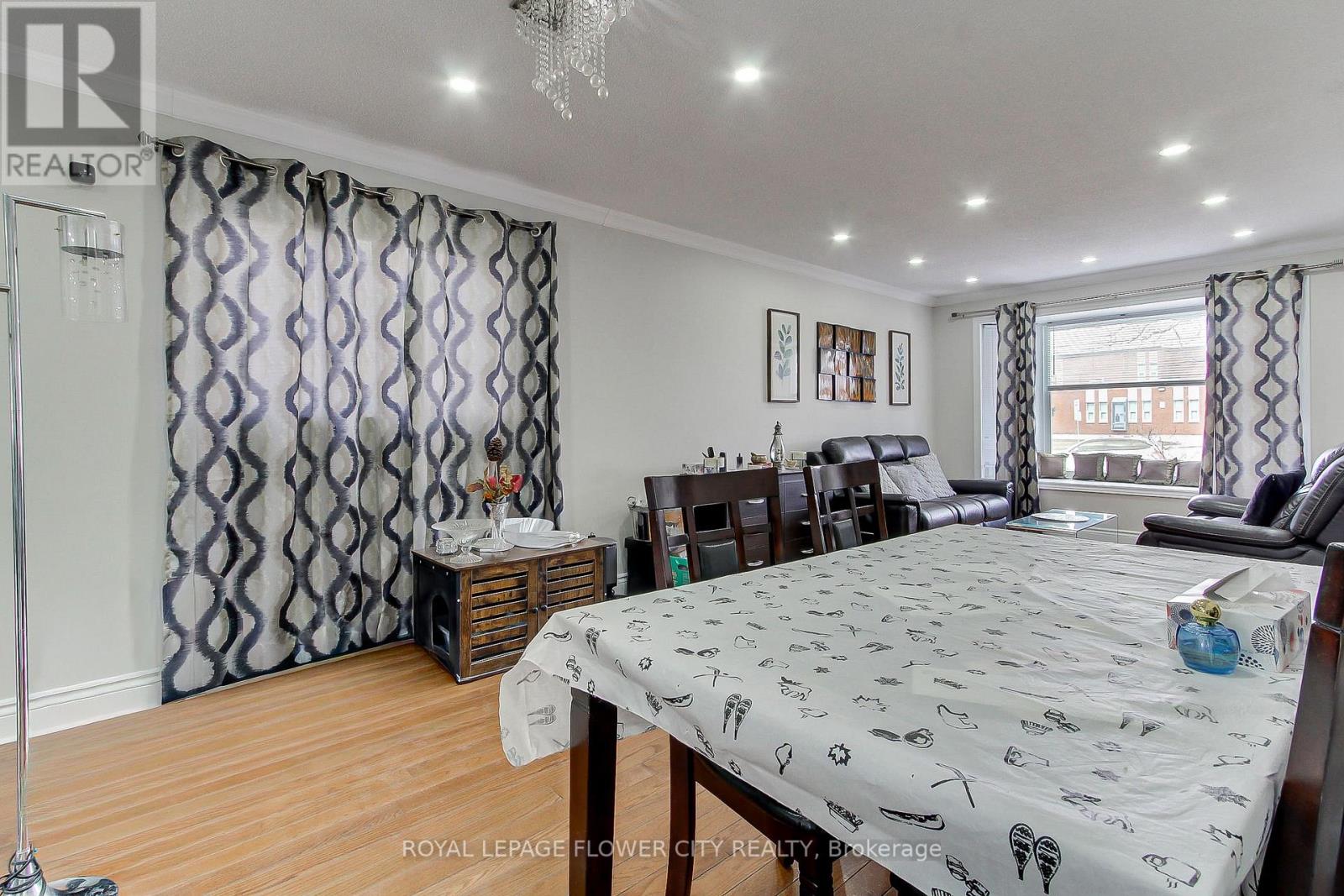 A bedroom with a large bed and a dining area in the background.