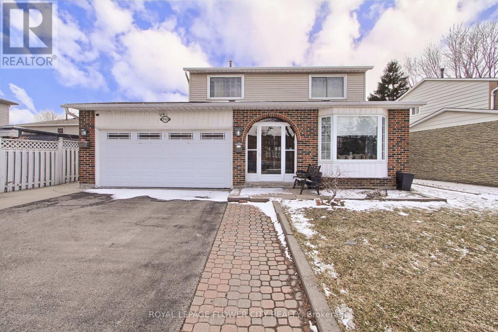 A house with a white garage door and a brick walkway leading to it.