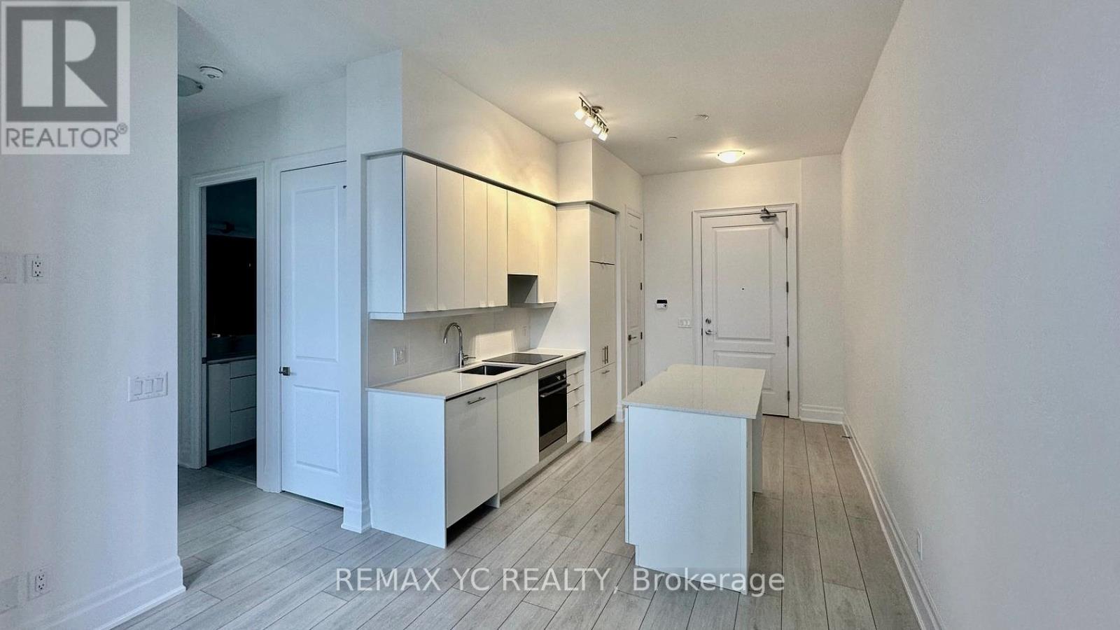 A white kitchen with a sink and a refrigerator.