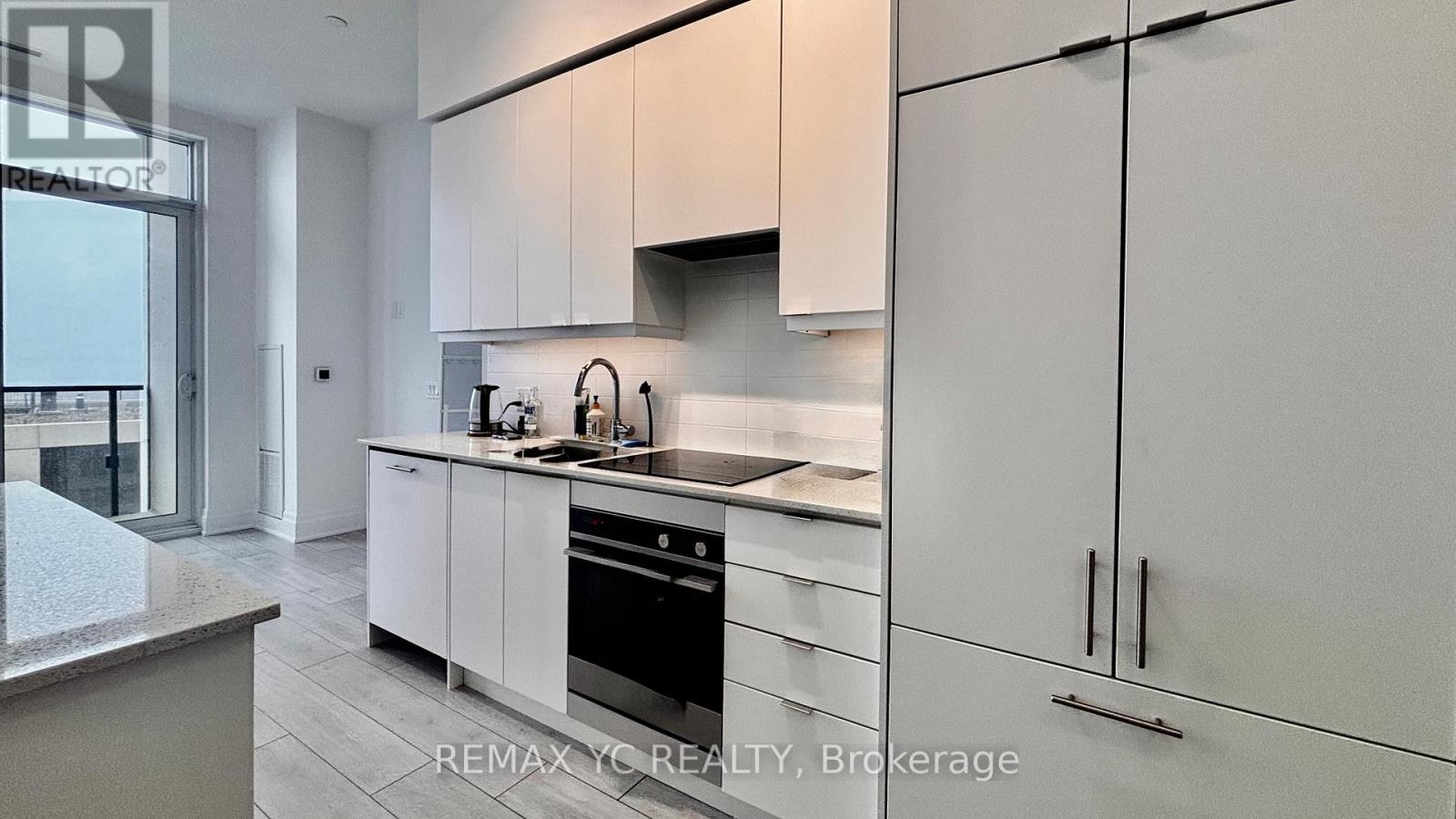 A modern kitchen with white cabinets and stainless steel appliances.