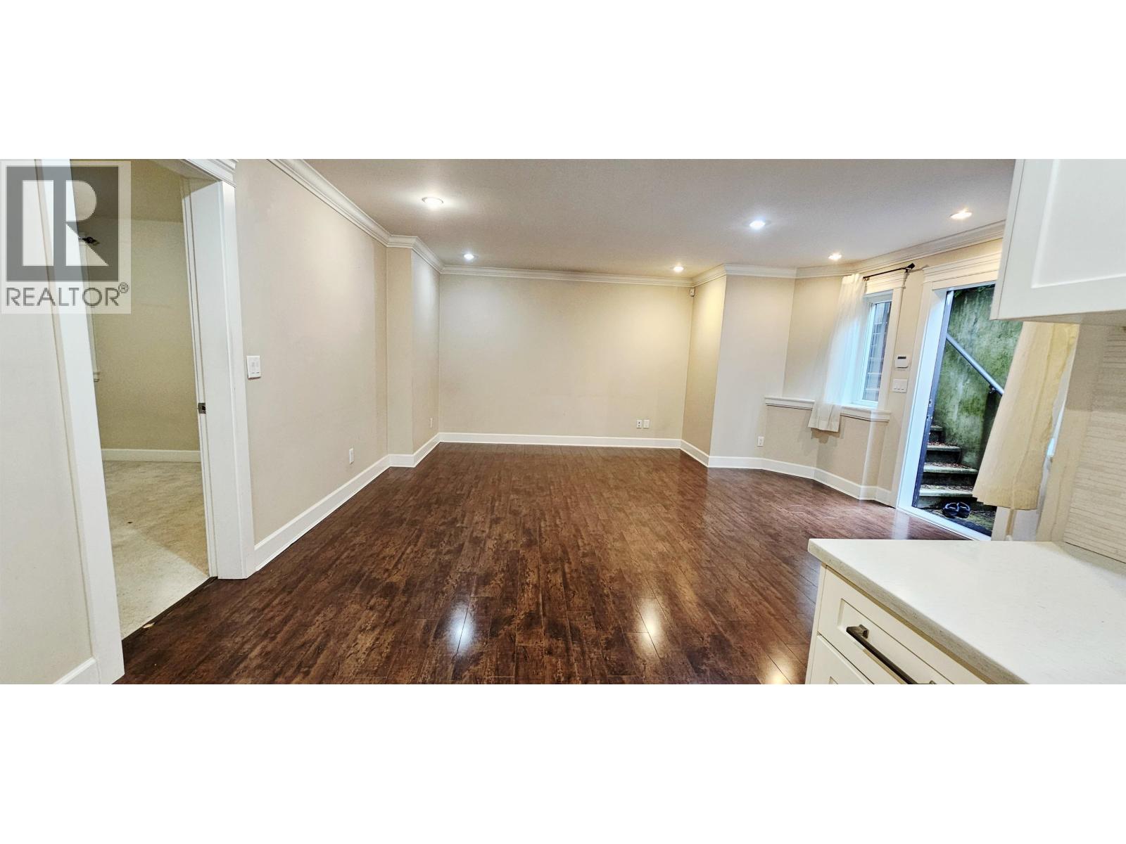 A spacious room with wooden flooring and white walls.