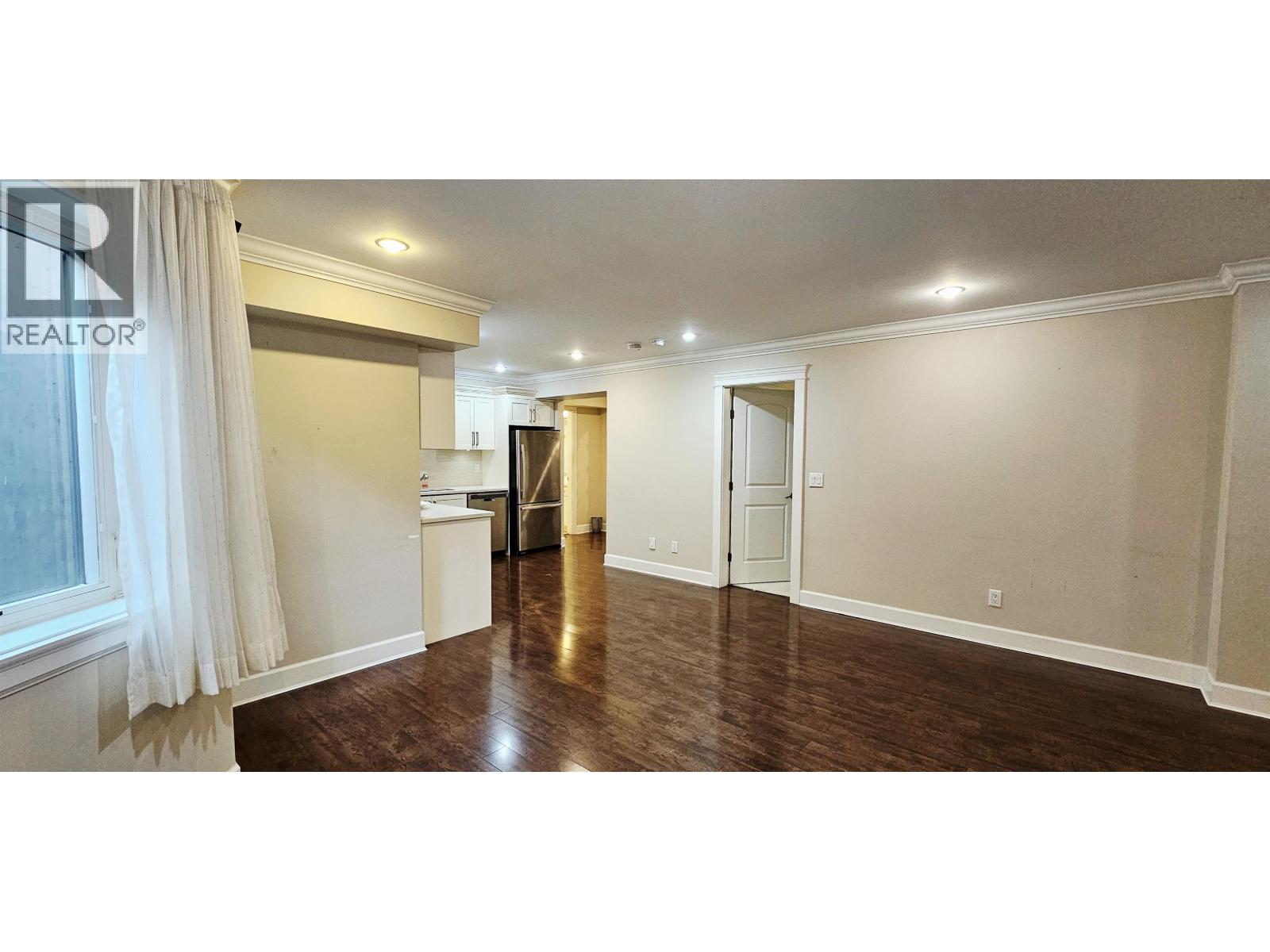 A spacious room with wooden floors and white walls.