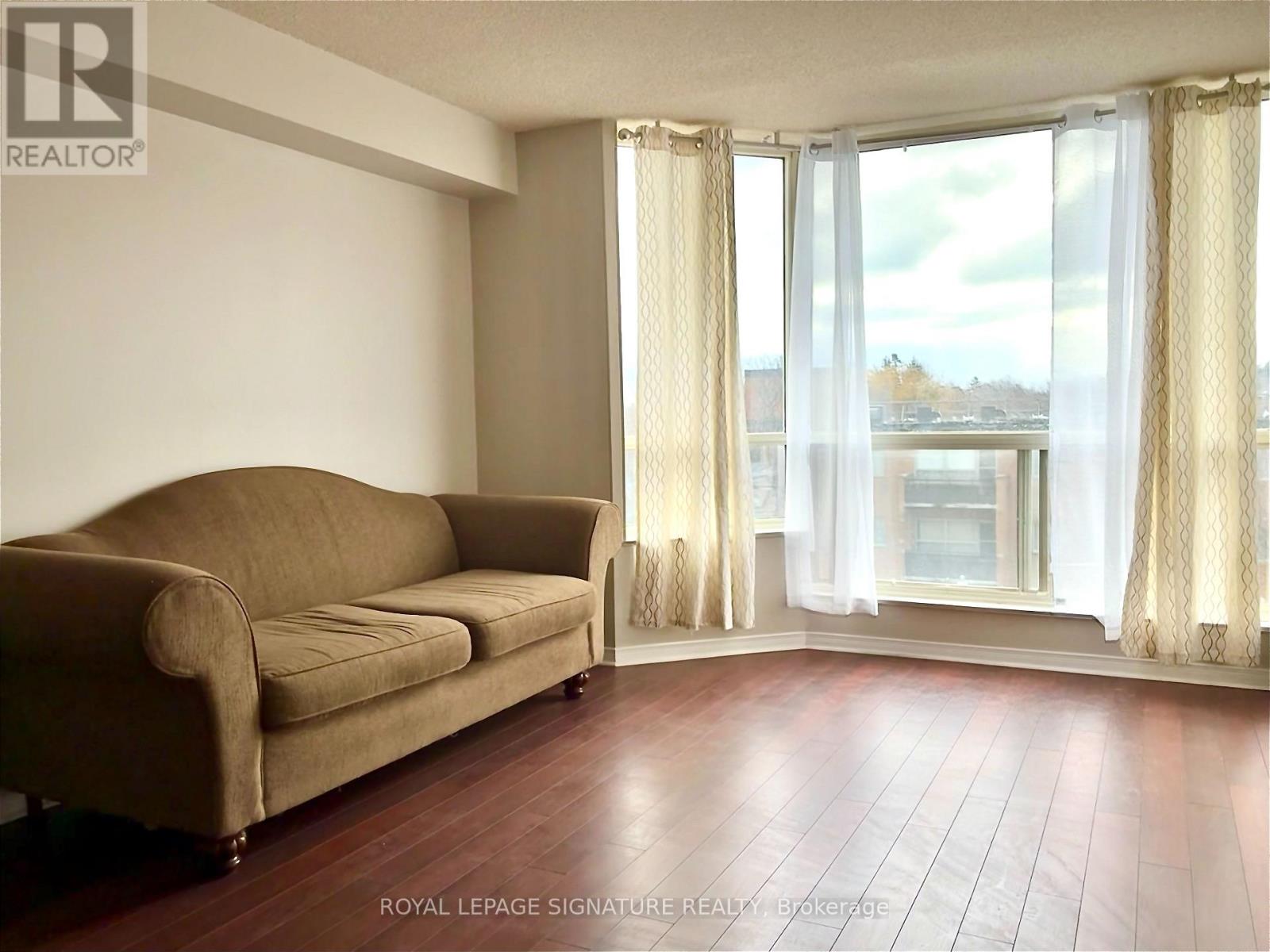 A living room with a couch and a window with curtains.