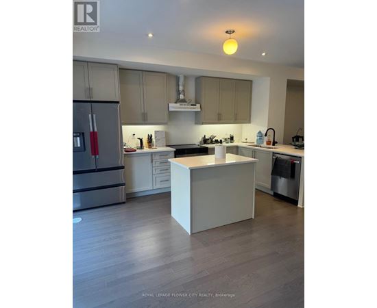 A modern kitchen with a white island and wooden floors.