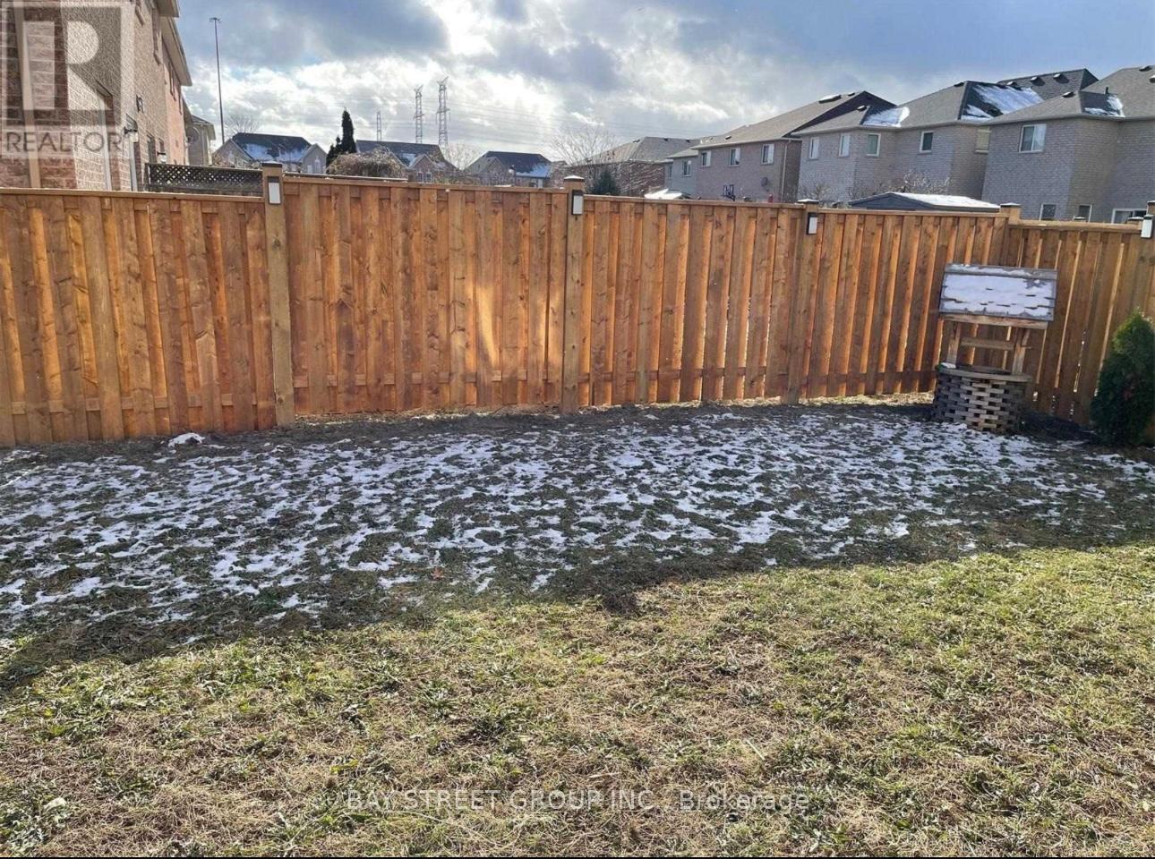 A wooden fence with a sign on it in front of a grassy area.
