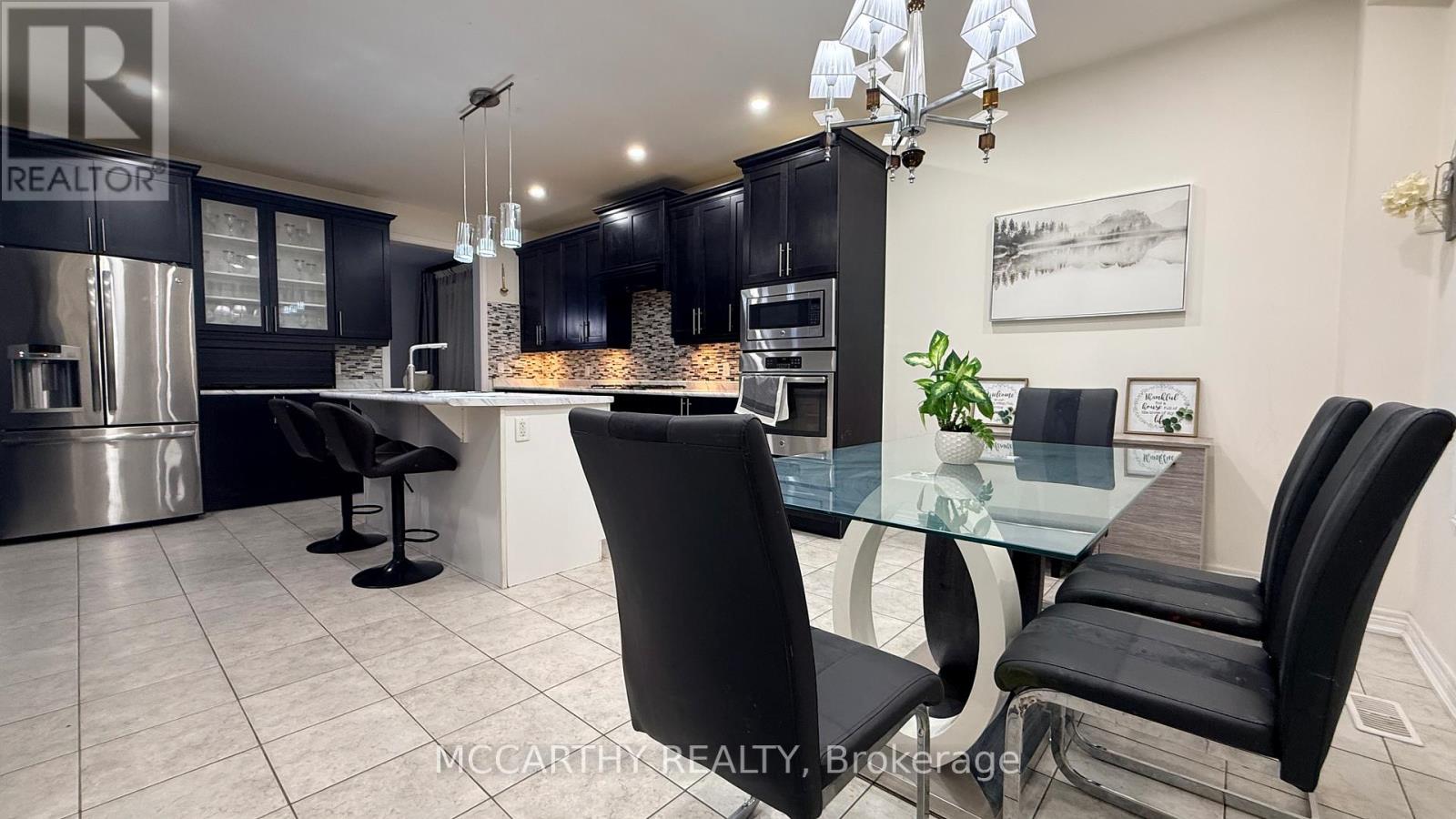 A modern kitchen with a glass table and black chairs.