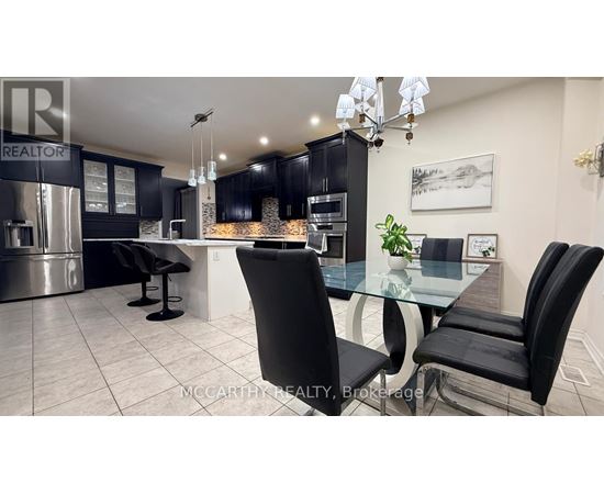 A modern kitchen with a glass table and black chairs.