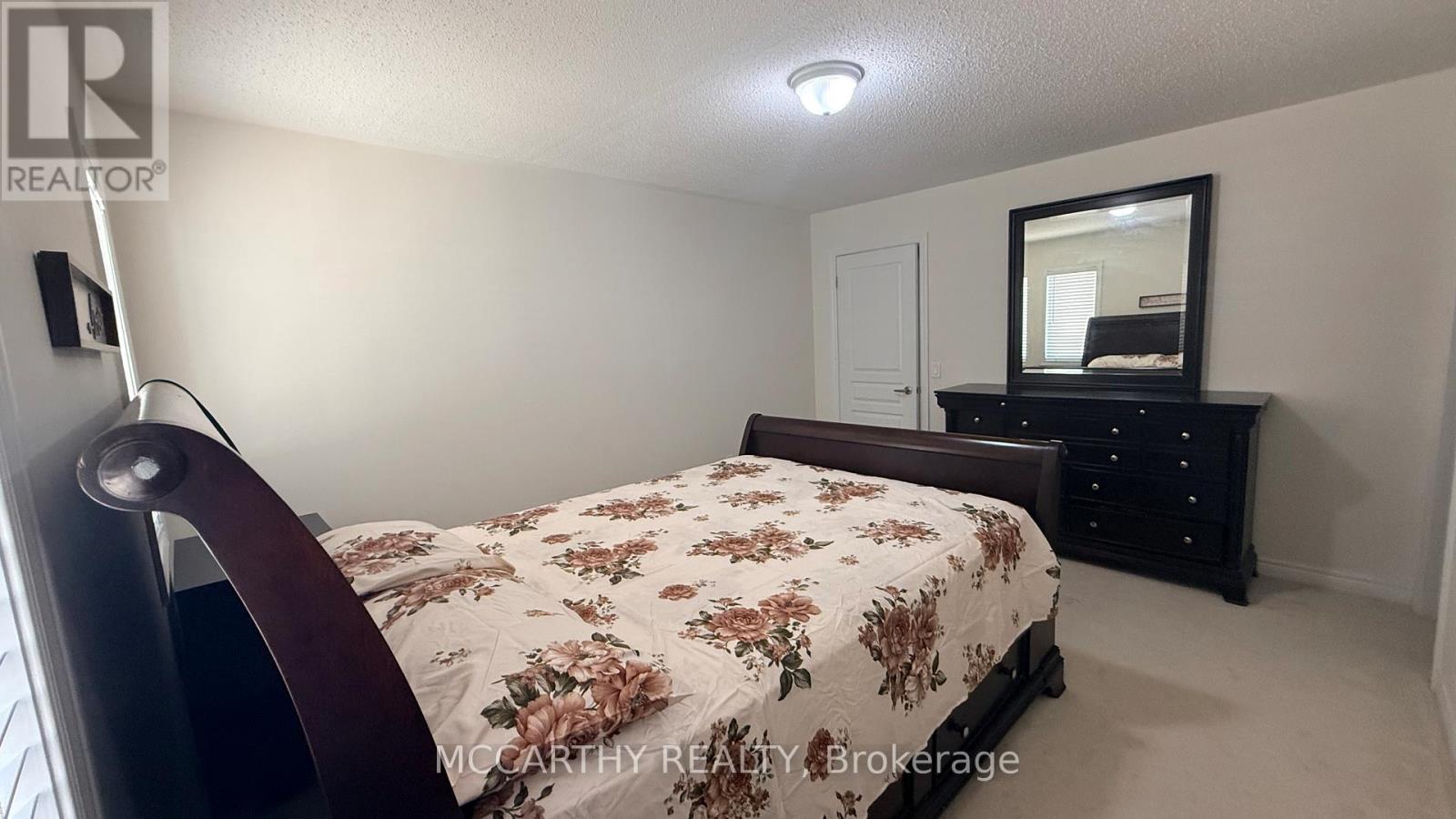 A bedroom with a floral bedspread and a mirror on a dresser.