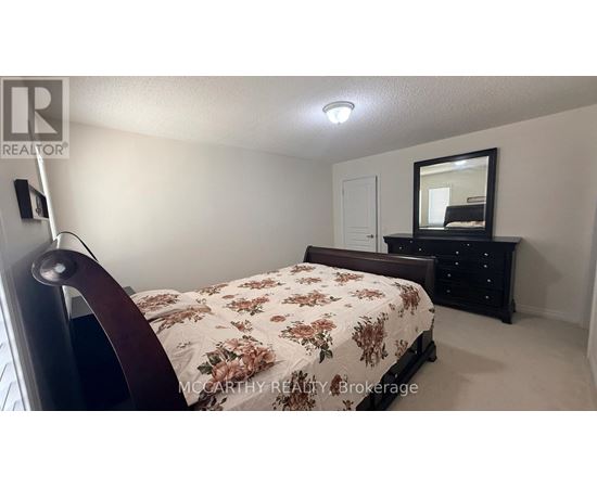 A bedroom with a floral bedspread and a mirror on a dresser.