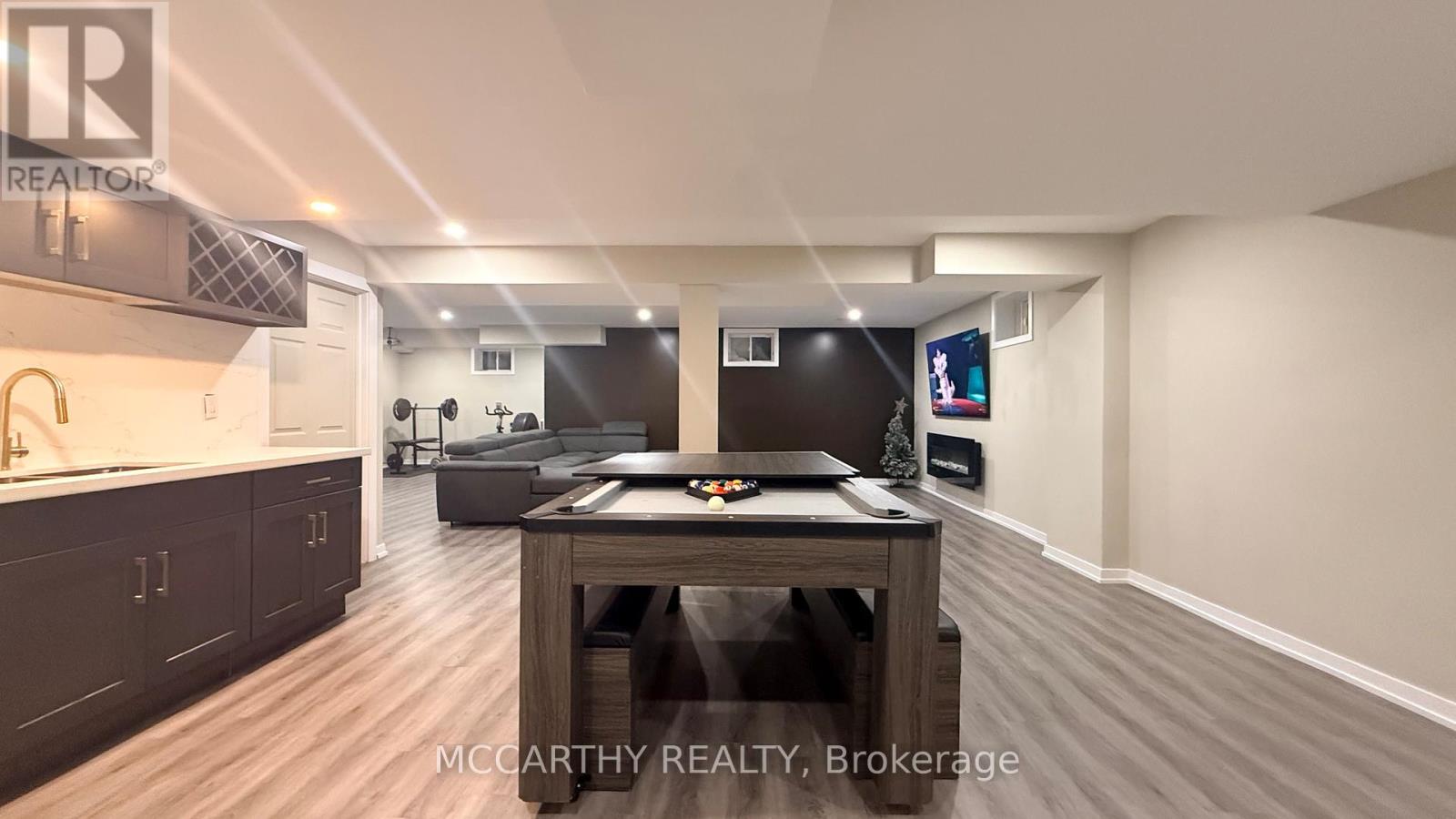 A spacious room with a wooden table and a TV mounted on the wall.