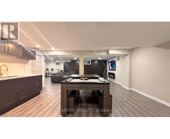 A spacious room with a wooden table and a TV mounted on the wall.