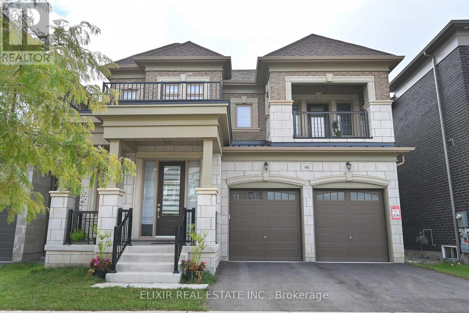 A two-story house with a balcony on the upper floor and a garage on the lower floor.