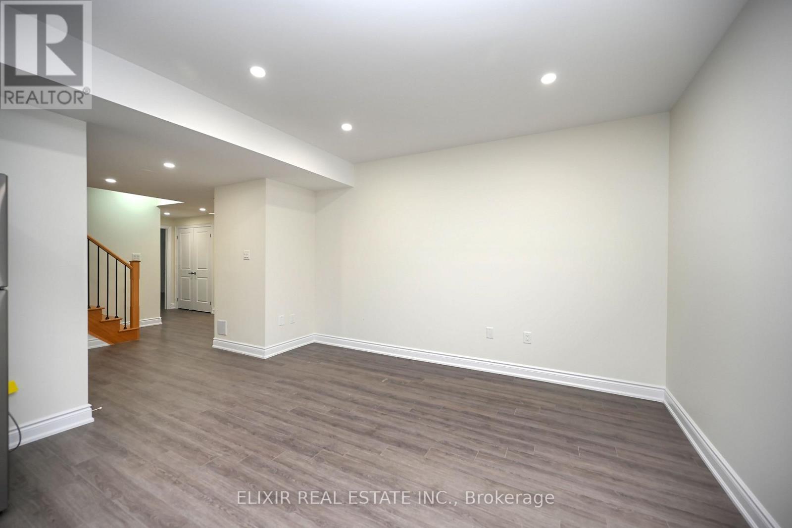 A spacious room with wood flooring and white walls.