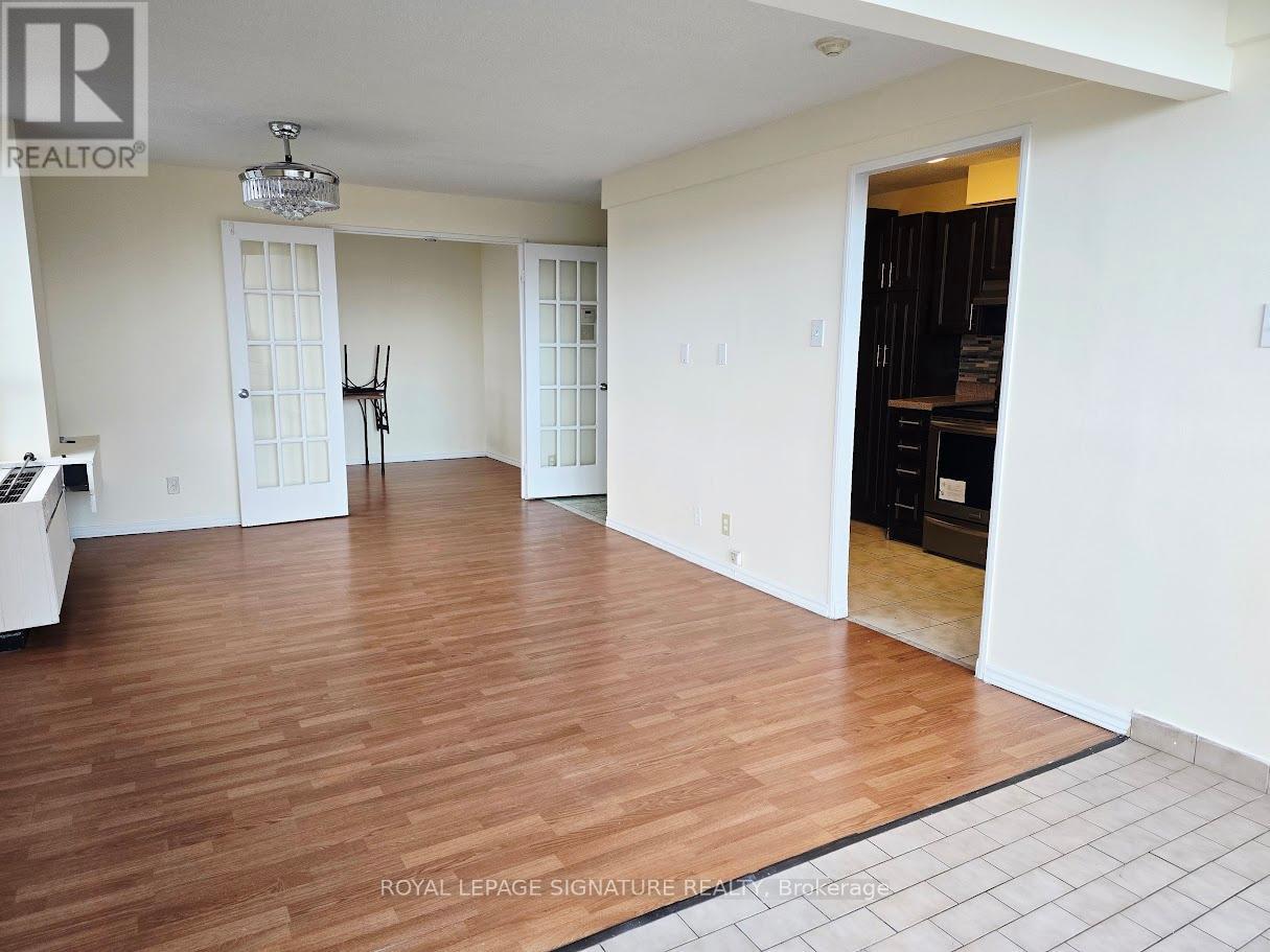 A spacious room with wooden flooring and white walls.
