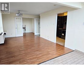 A spacious room with wooden flooring and white walls.