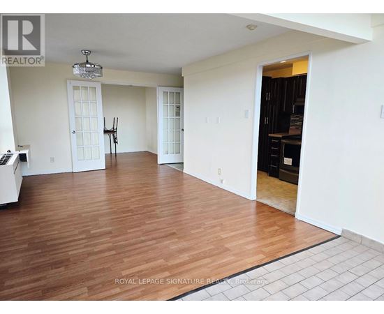 A spacious room with wooden flooring and white walls.