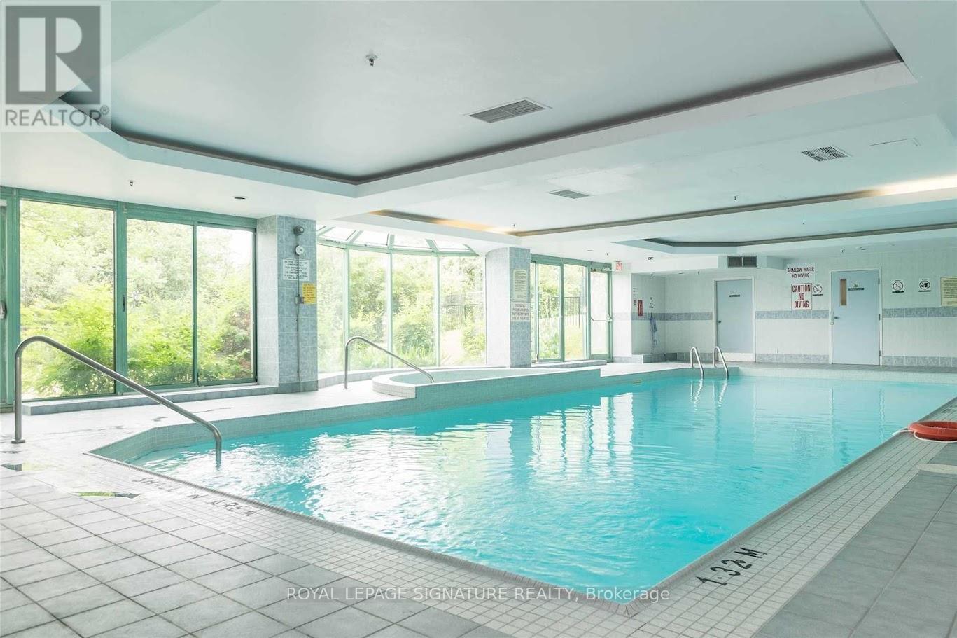 A large indoor swimming pool with a glass wall on one side.