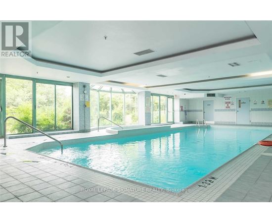 A large indoor swimming pool with a glass wall on one side.