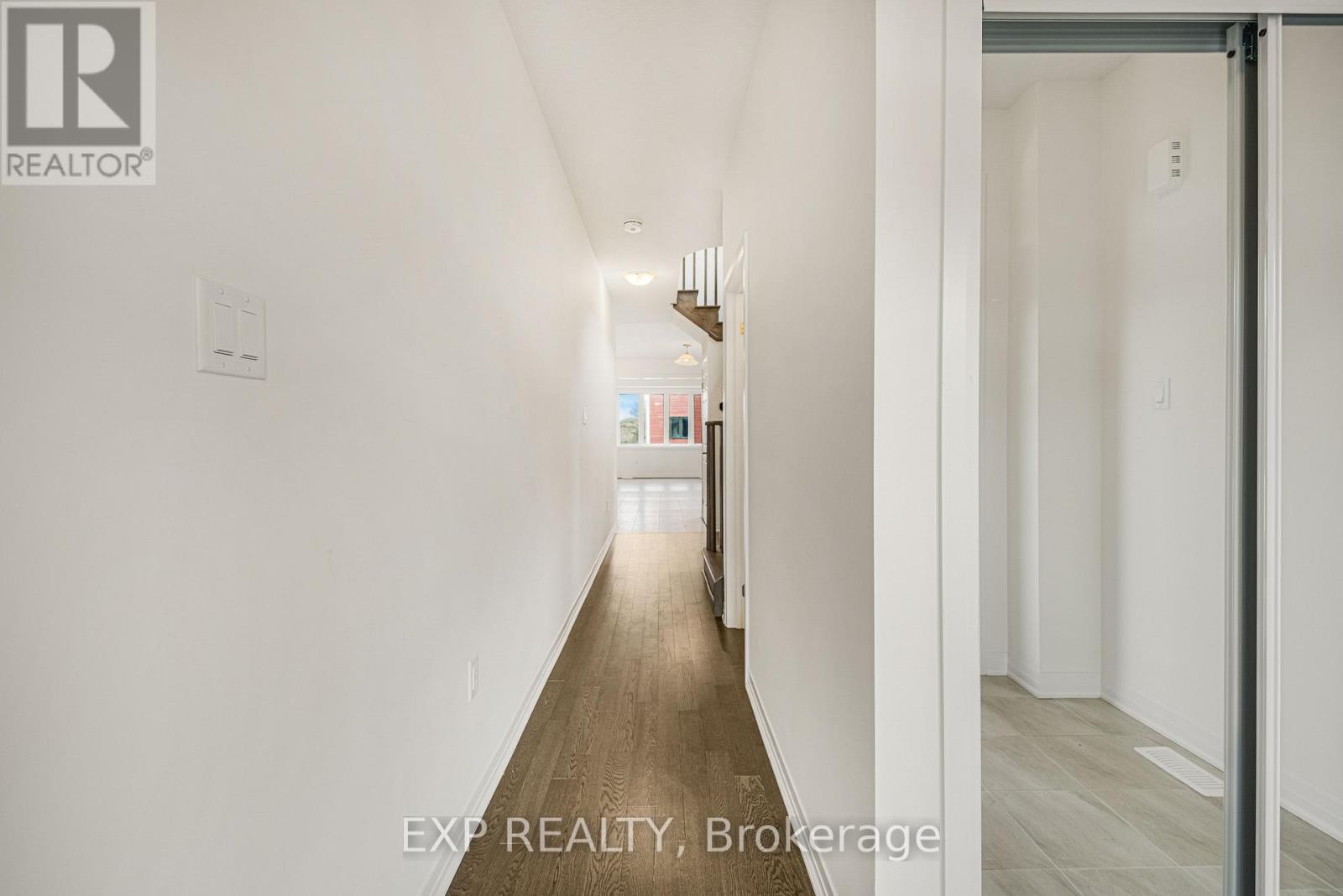 A long, narrow hallway with white walls and wood flooring.