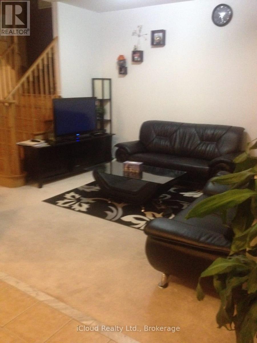 A living room with a black leather couch and a television.