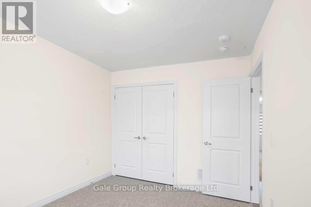 A white bedroom with two doors and a carpeted floor.