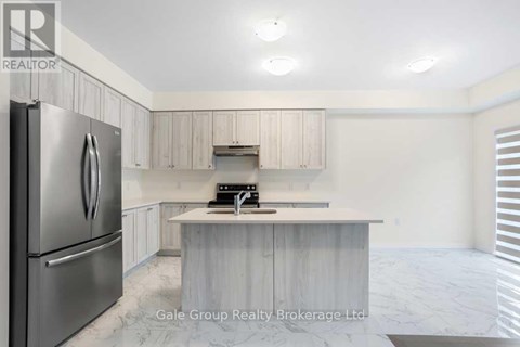 A modern kitchen with a stainless steel refrigerator and a marble countertop.