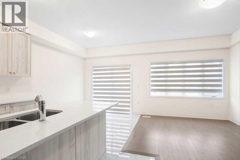 A modern kitchen with a sink and a window with blinds.