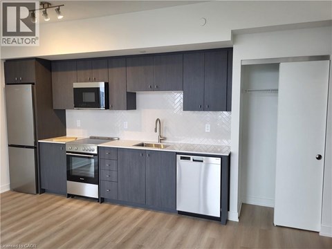 A modern kitchen with dark wood cabinets and stainless steel appliances.