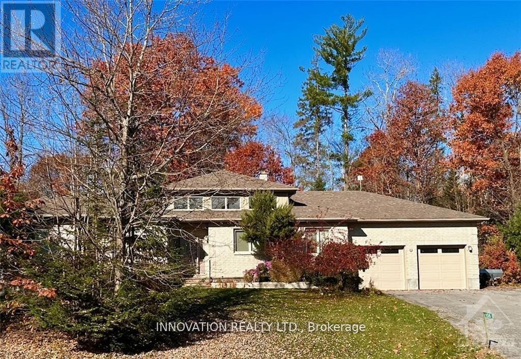 A house with a brown roof and a garage is surrounded by trees with orange leaves.