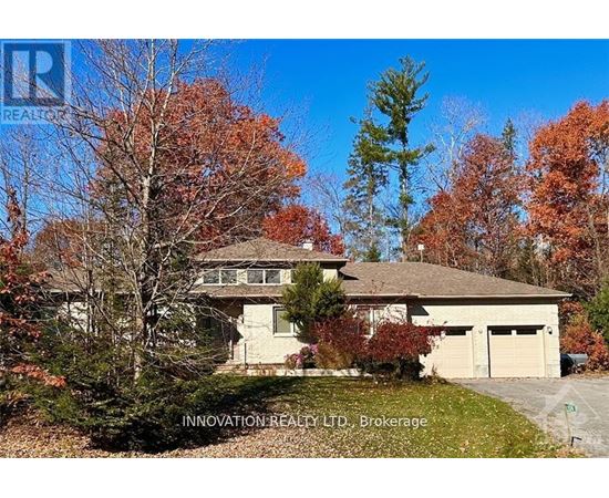 A house with a brown roof and a garage is surrounded by trees with orange leaves.