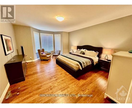 A bedroom with a large bed and a wooden floor.