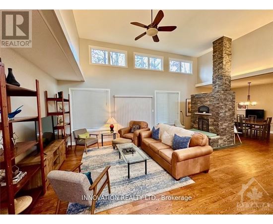 A living room with a stone fireplace and a brown couch.