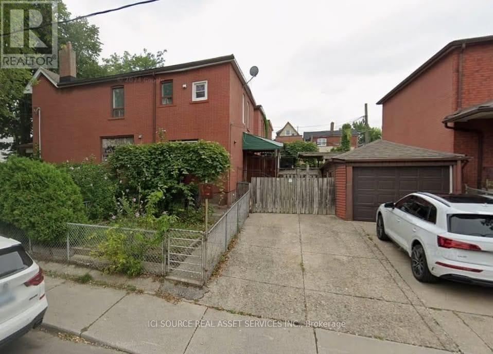A white car is parked in a driveway in front of a red brick house.