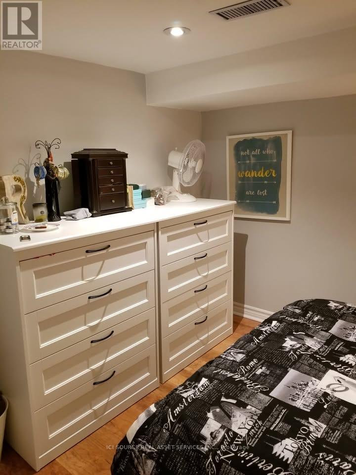 A bedroom with a bed, dresser, and a fan.